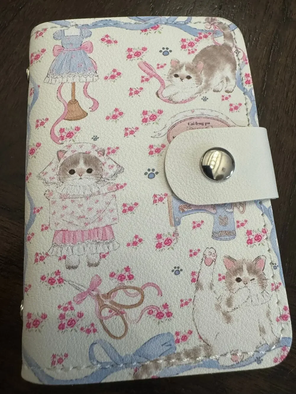 White cat-themed card wallet with pink floral and sewing-themed illustrations